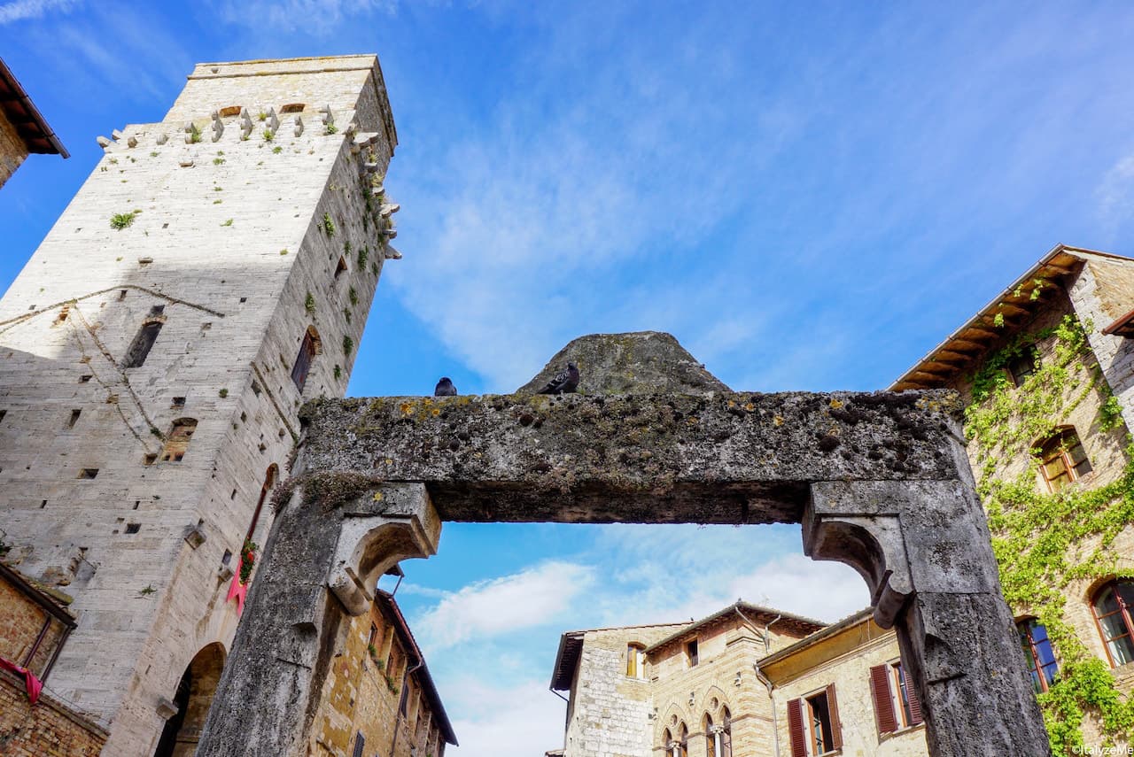 Pozzo di Piazza della Cisterna con l'imponente mole della Torre del Diavolo